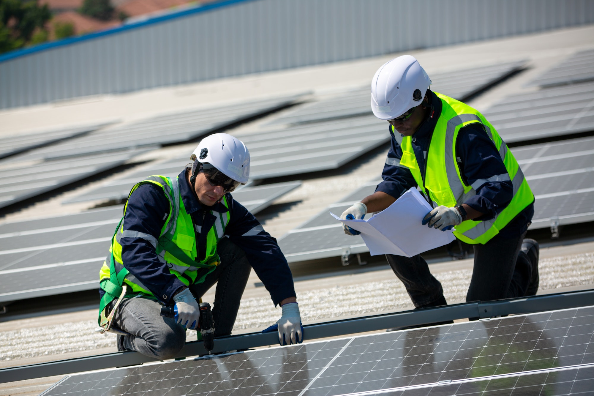 Solar panel installer installing solar panels on roof of warehouse